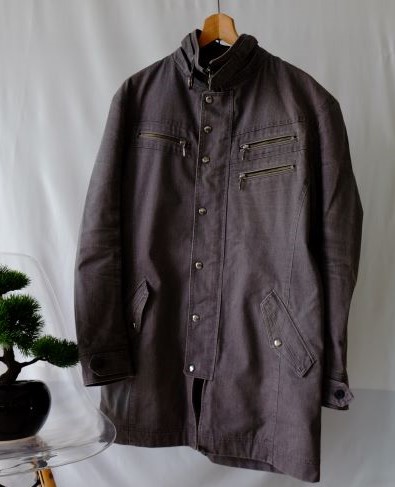เสื้อแจ็คเก็ตสีเทา(ช) แต่งด้วยซิปและกระดุมแป๊กมีกระเป๋าด้านหน้า มีลูกเล่นบริเวณคอ แขนยาวและด้านหลัง Michel Klein size XL
