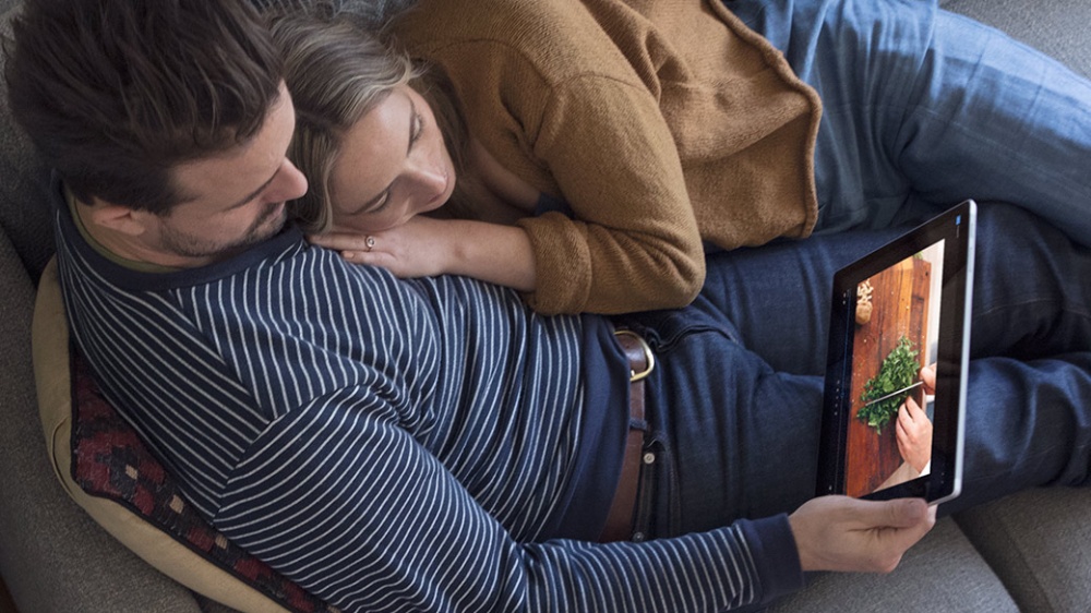 Man and woman lounging together while interacting with a Surface Pro